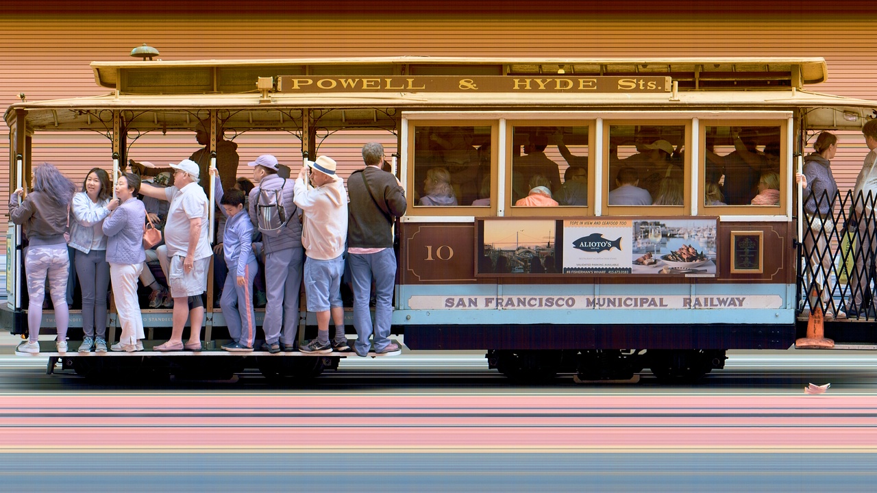 Cable car climbing a steep San Francisco street with city skyline