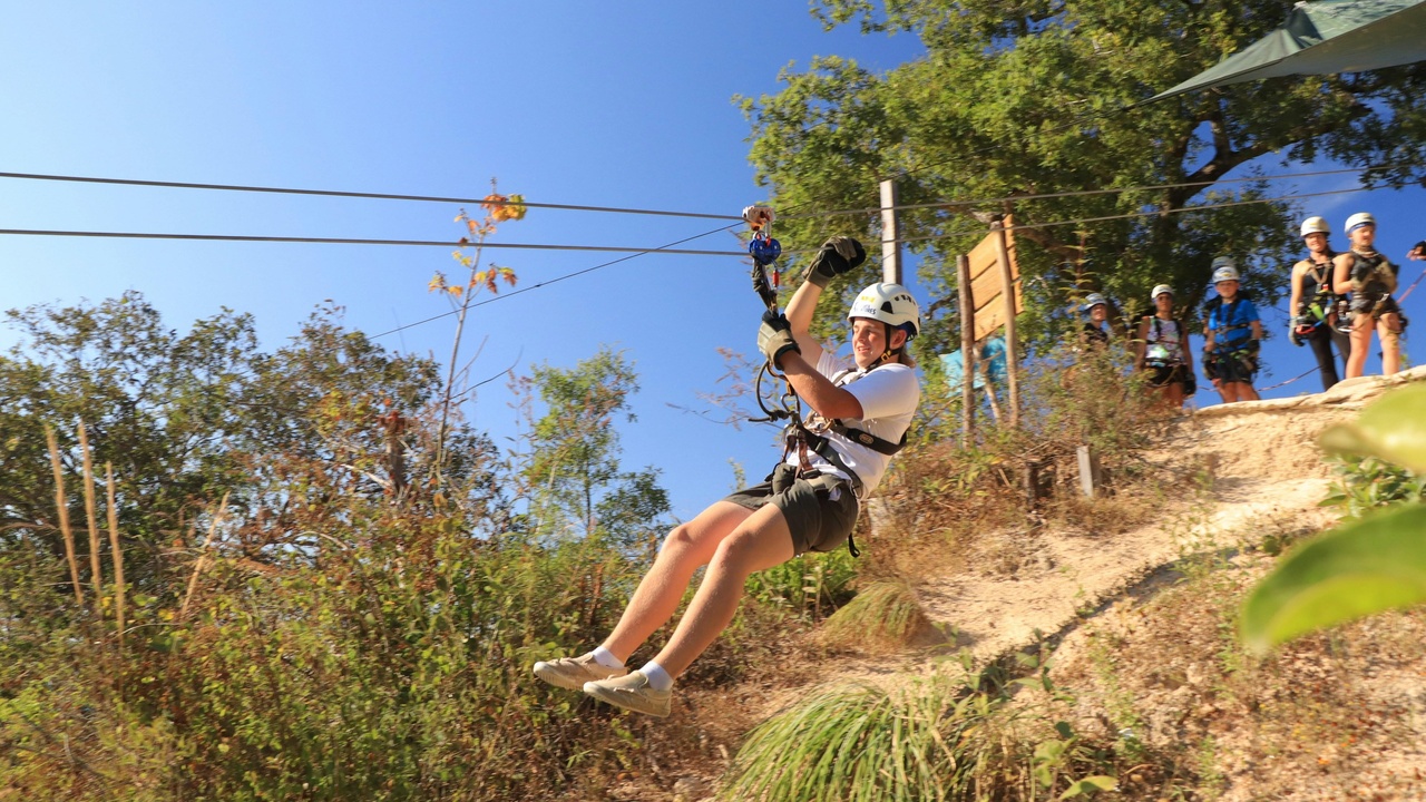 Person mid-zipline over green jungle canopy near Puerto Vallarta