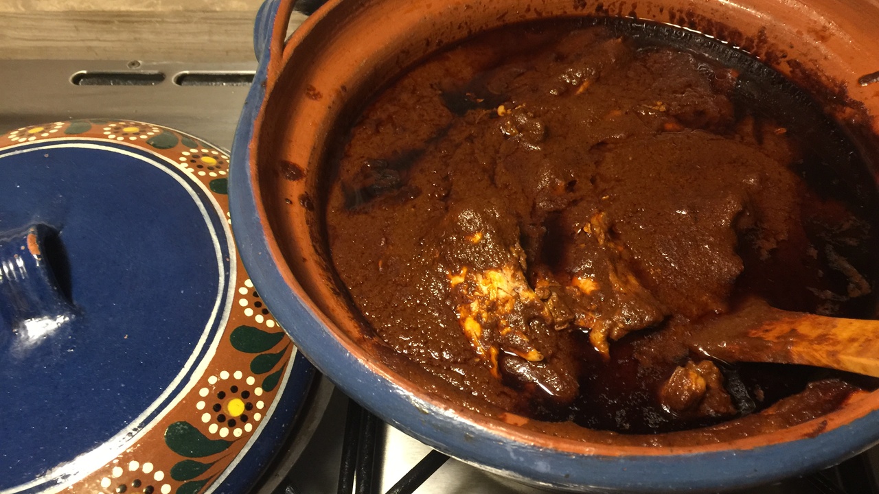 Cooking mole with traditional mortar and pestle (metate).