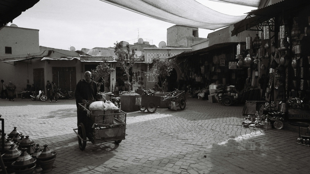 A busy Iraqi market street with families and small shops, showing neighborhood life