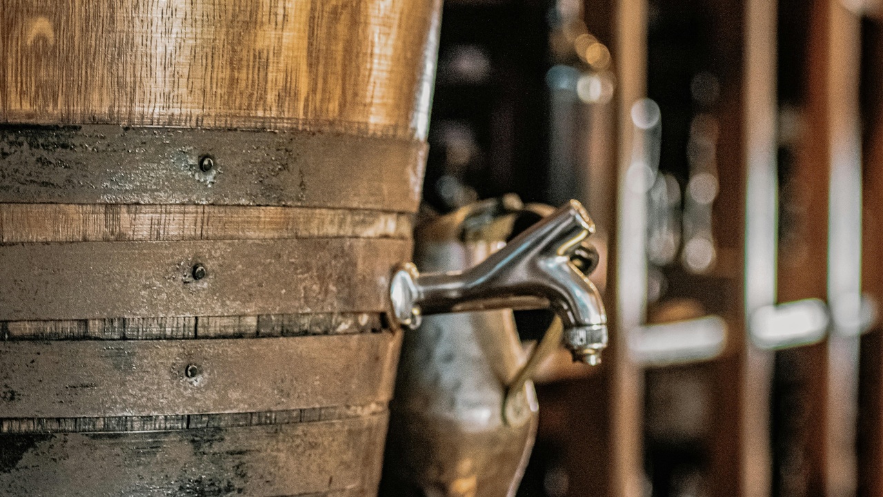 Plate of flying fish and cou-cou beside a Mount Gay Rum bottle and a lively Oistins Fish Fry scene
