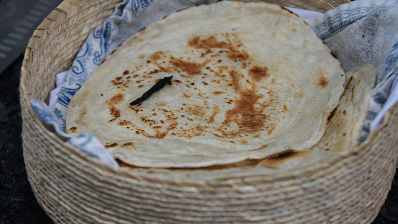 Plate of cabrito with tortillas and a view of a lively Barrio Antiguo street at night