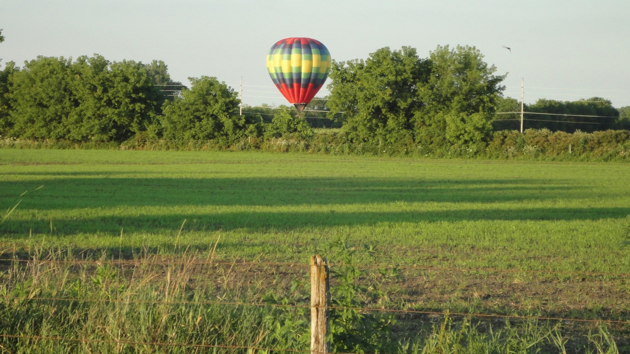 Hot-air balloons rising over the Texas Hill Country at sunrise.