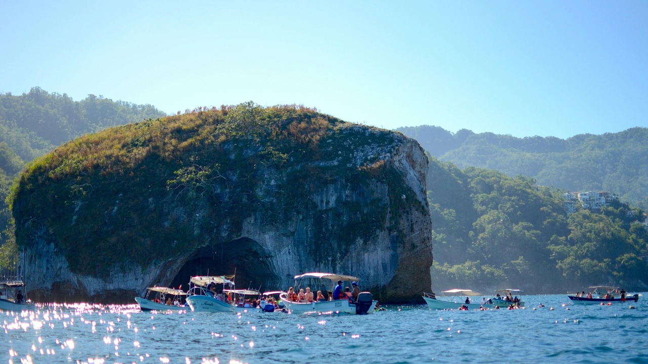 Small tour boat near rocky islets in Banderas Bay with snorkelers prepping to enter the water