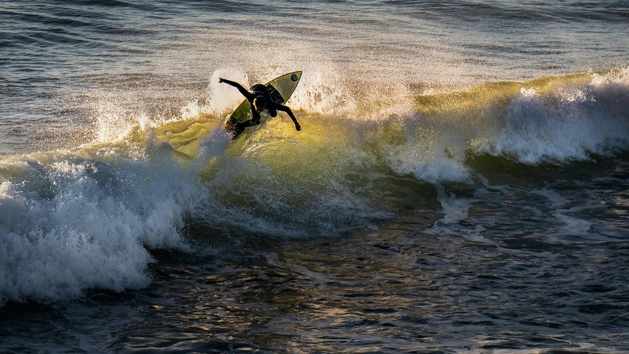 Surfers at Surfrider Beach riding a longpoint wave with Malibu Pier in background
