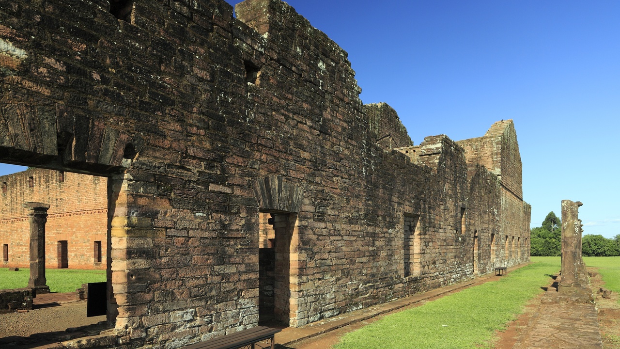 Stone ruins of a Jesuit mission with interpretive panels and grassy courtyard