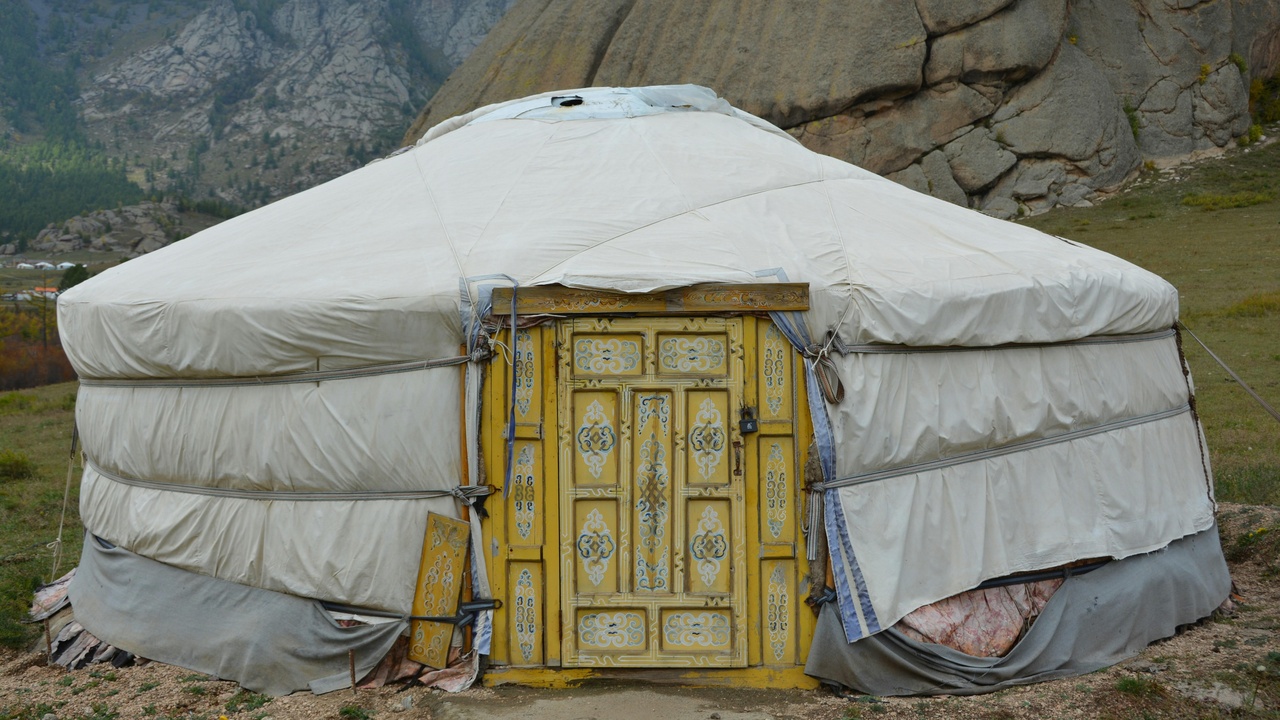 A family in a ger camp and a Kazakh eagle hunter displaying a golden eagle