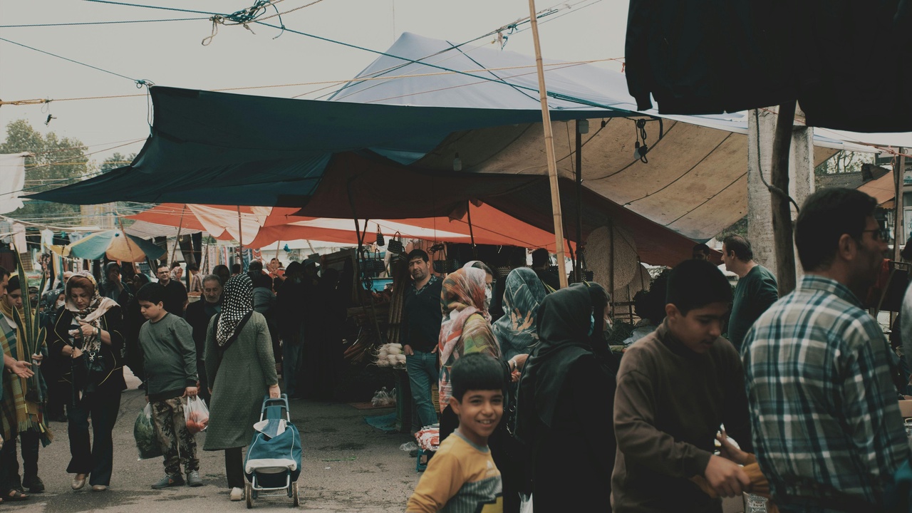 Busy Kabul bazaar showing traders and handmade carpets.