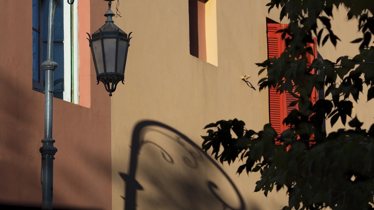 Colorful houses of La Boca with tourists photographing Caminito and the cobbled street.