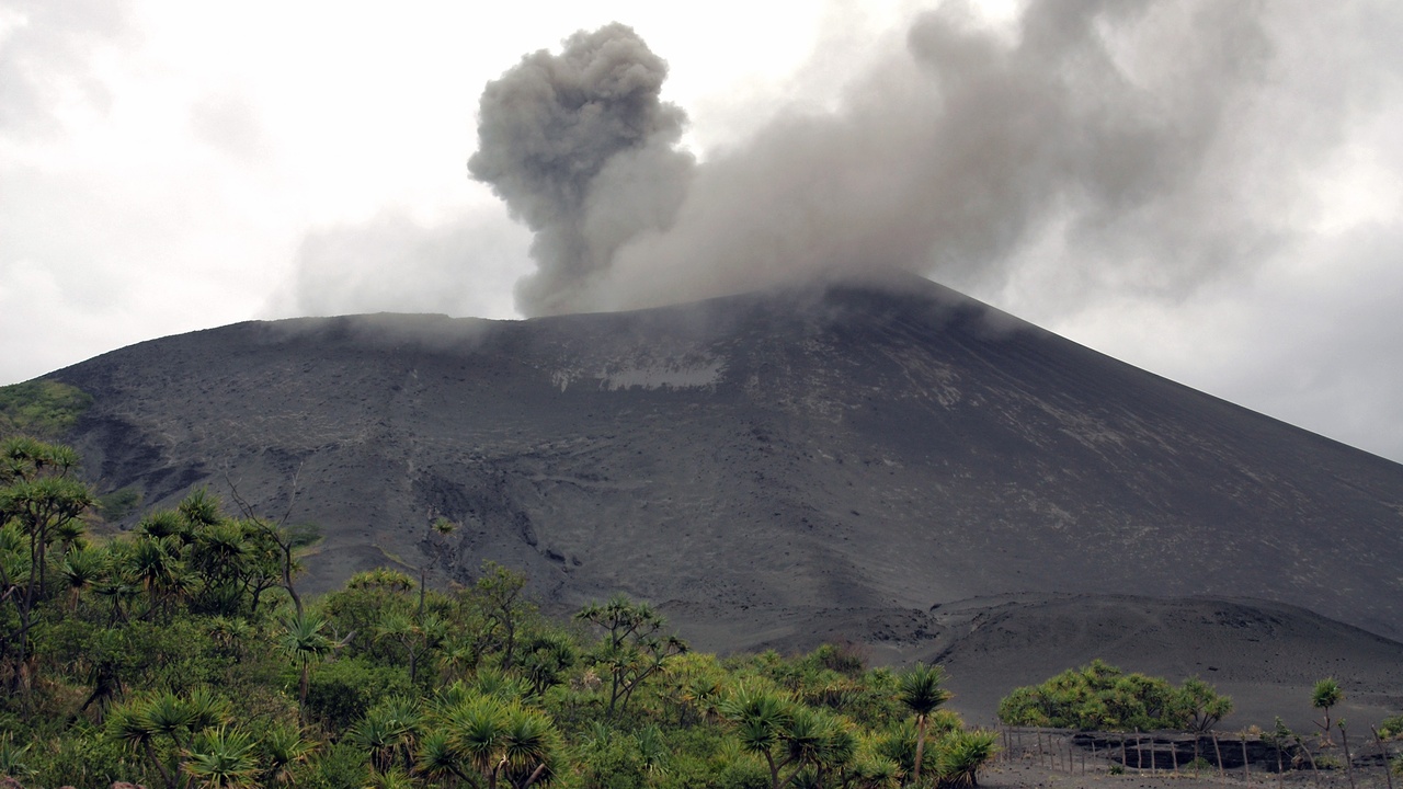 Mount Yasur erupting on Tanna island with visitors viewing from a ridge.