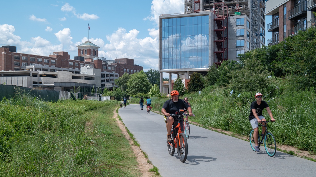 Urban trail users on the Atlanta BeltLine with greenery and river paddling nearby