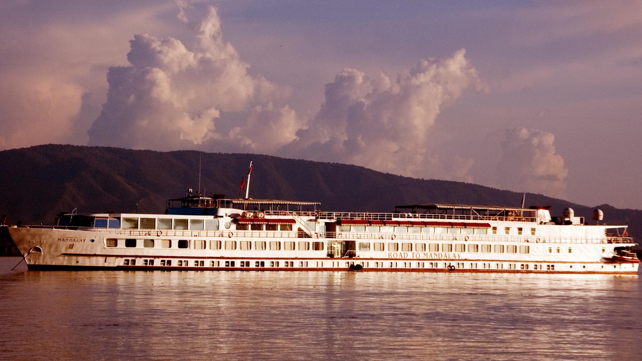 Boat on the Ayeyarwady River with riverside villages at sunset