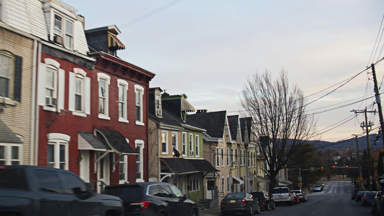 Suburban street with sidewalks, single-family homes, and police cruiser parked nearby.