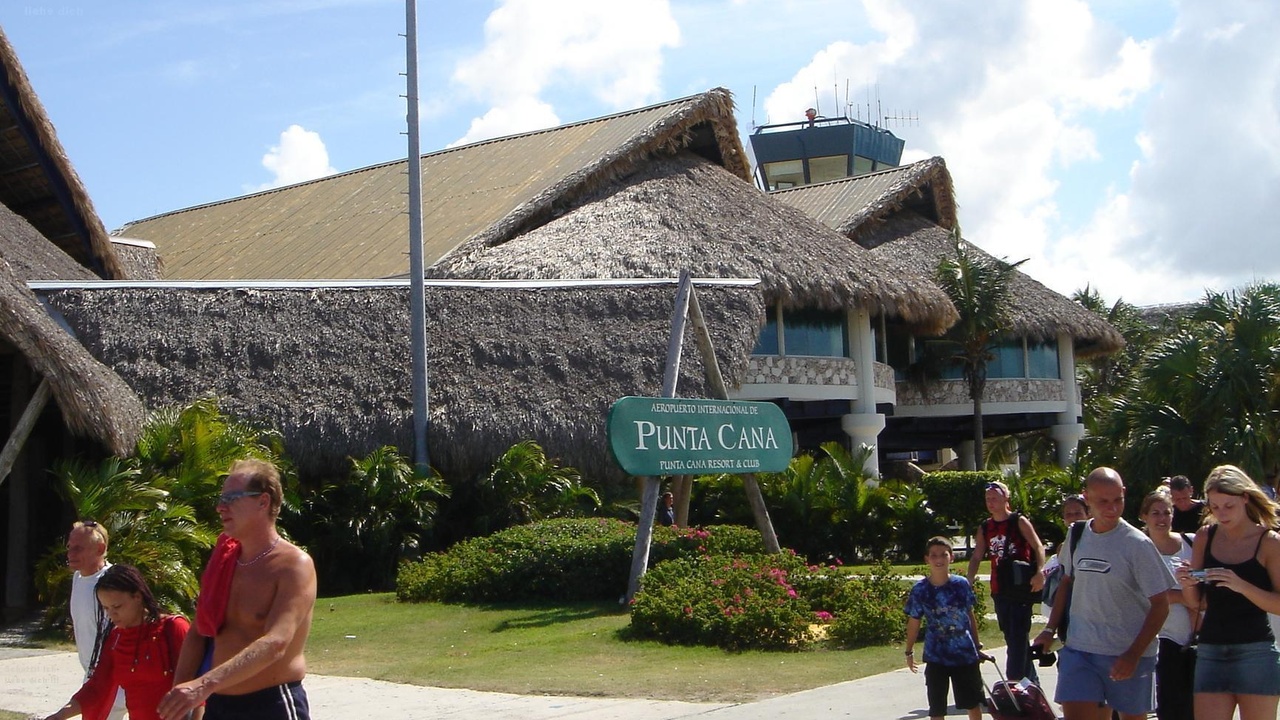 Passengers disembarking at Punta Cana International Airport with resort shuttles in view