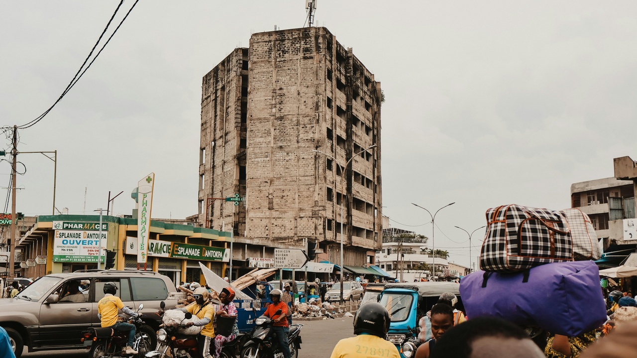 Busy Benin highway with mixed traffic including trucks and motorcycle taxis