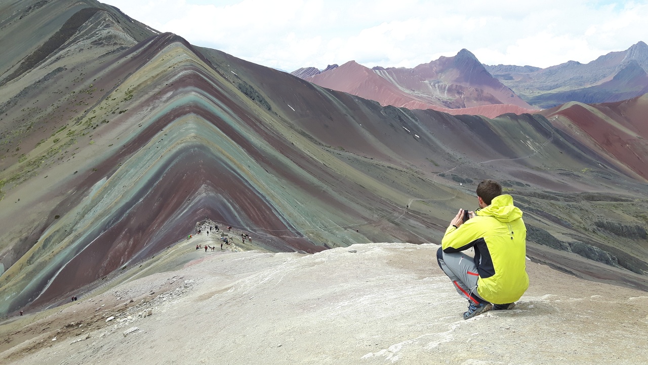 Hikers at Rainbow Mountain showing colorful mineral stripes.