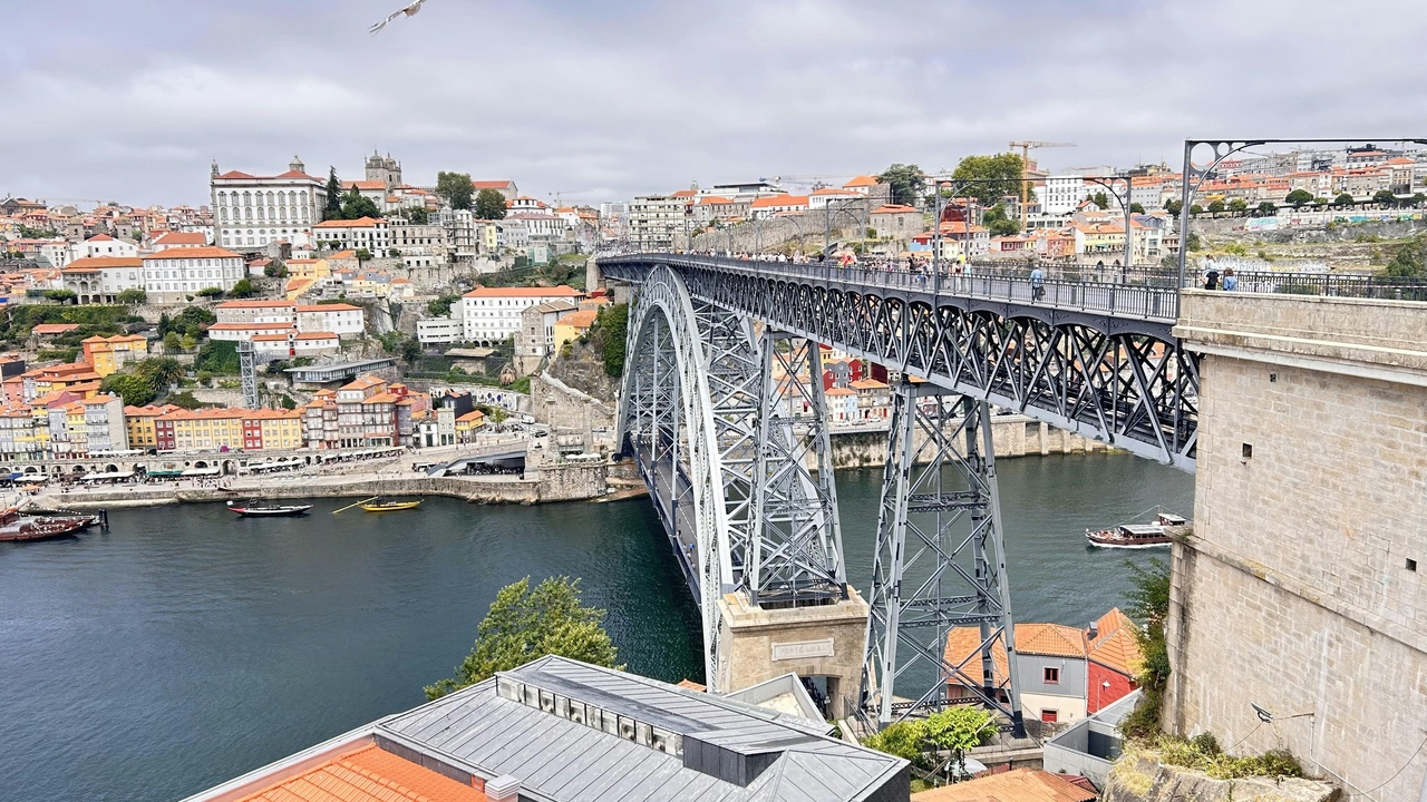 Crowded Ribeira riverside with tourists and occasional rainy skies in Porto