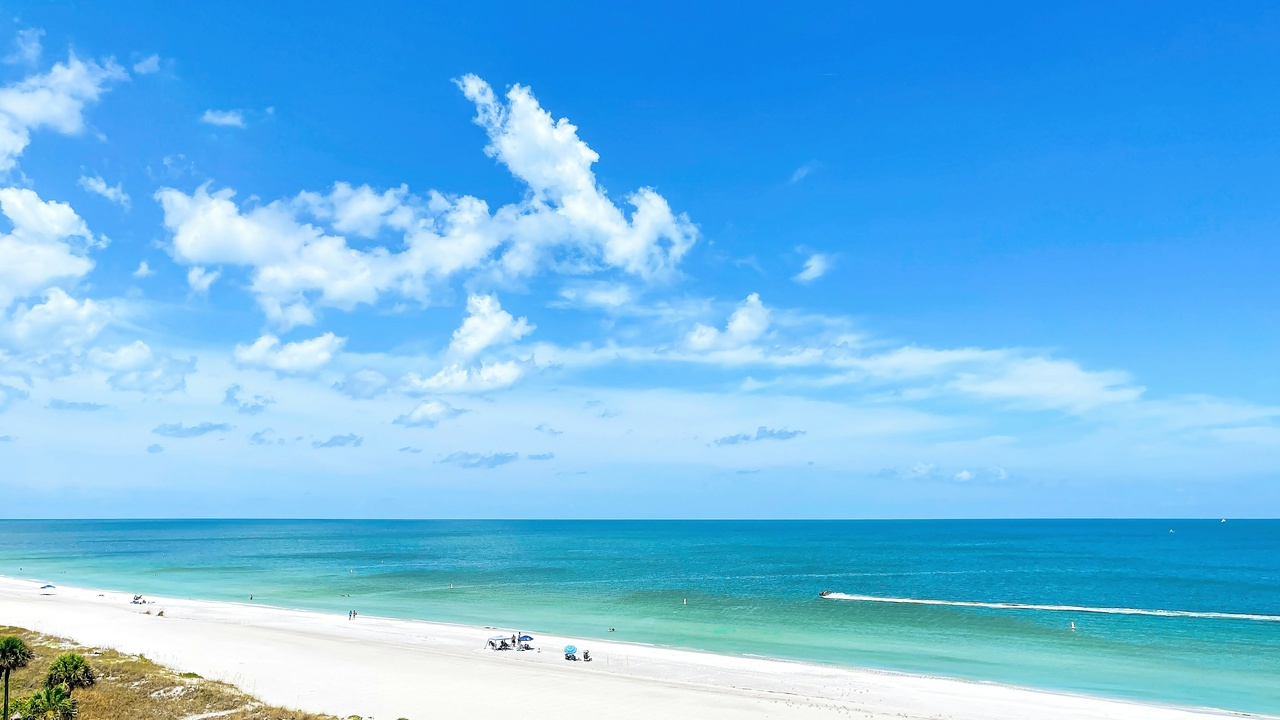 Wide view of Clearwater Beach with white sand and people enjoying the shoreline at sunset