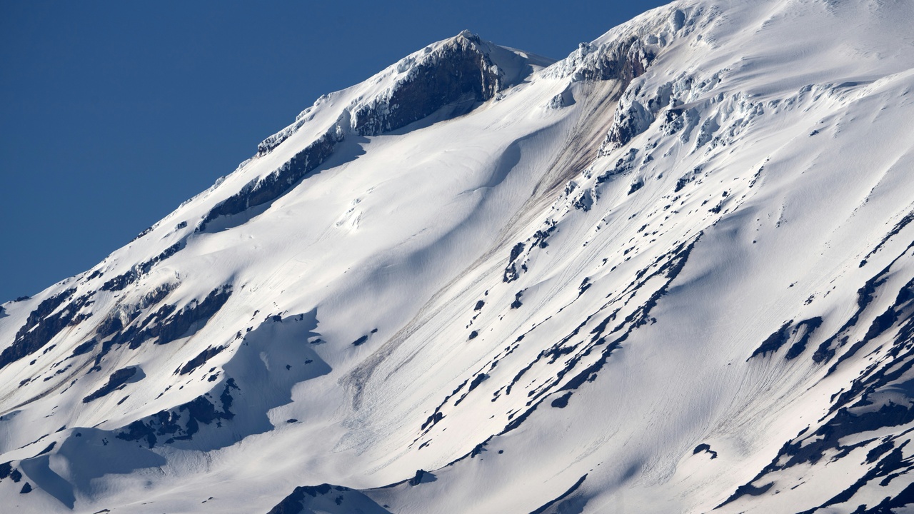Hikers on a high alpine ridge with rocky summits and distant mountain views in the White Mountains.