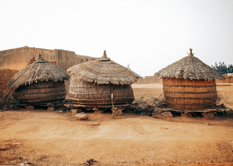 Three traditional thatched huts in an African village landscape. Rustic and cultural.
