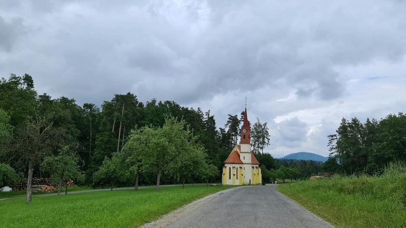 A picturesque church located amidst lush greenery and cloudy skies in rural Austria.