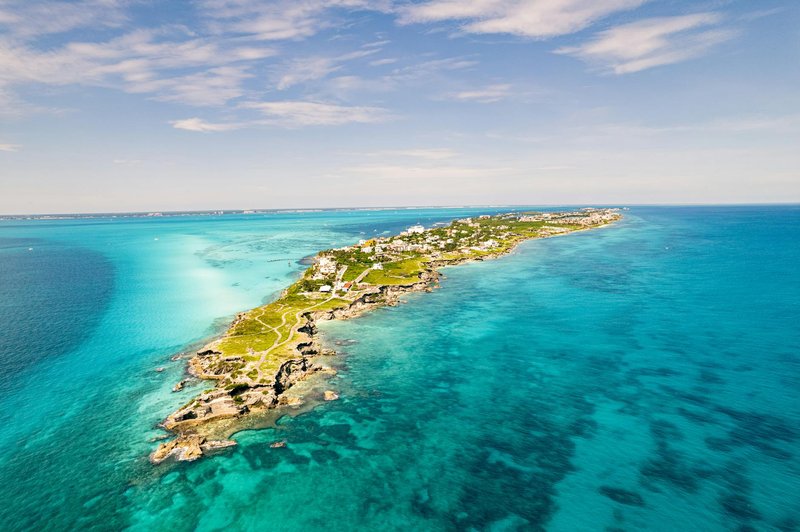 Breathtaking aerial view of Isla Mujeres, vibrant turquoise waters, and lush greenery in the Caribbean Sea.