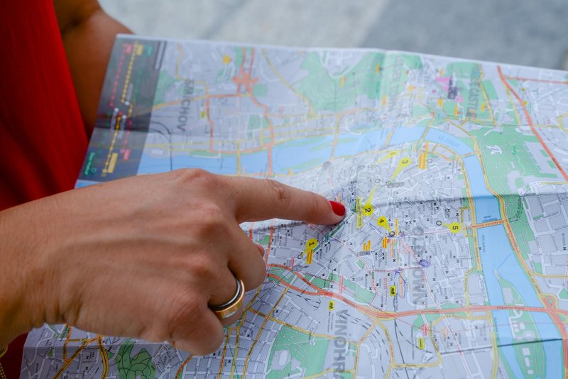 A person with a red shirt points at a city map indicating travel guidance. Perfect for tourism concepts.