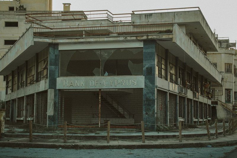 A vintage exterior of an abandoned Bank of Cyprus, with a worn and neglected facade.