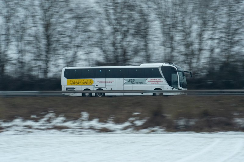 A dynamic shot of the Ingolstadt Airport Express bus speeding through a snowy landscape.