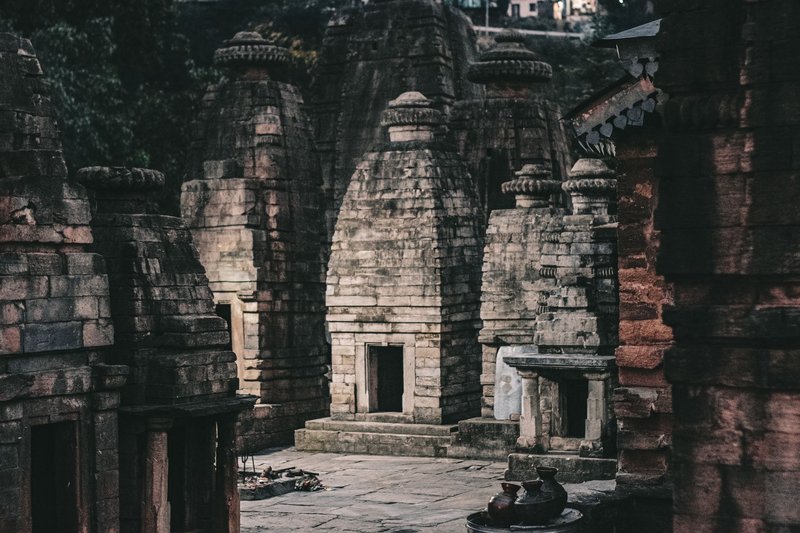 Ancient stone temples with intricate architecture in a moody, mystical setting.