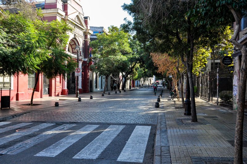 Charming street in Barrio Bellavista, Santiago with lush trees and colorful architecture.