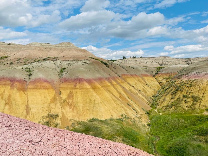 Colorful layered sedimentary rock formations under blue skies in Badlands National Park.