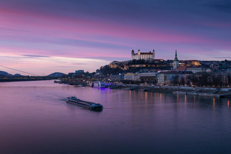 A picturesque view of Bratislava Castle and Danube River at sunset, showcasing Slovakia's scenic cityscape.