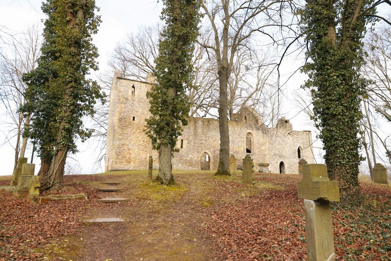 Explore historical church ruins surrounded by an old cemetery on a quiet, leaf-strewn hill.