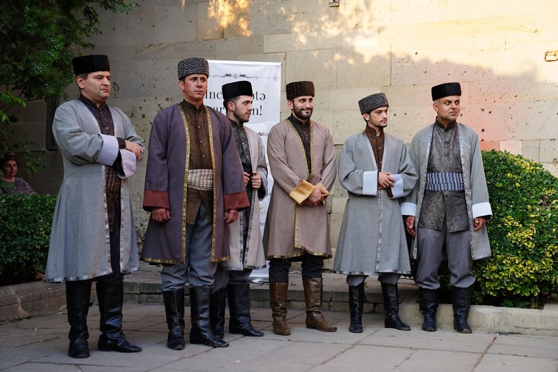Group of men in traditional Caucasian clothing at an outdoor event with cultural significance.