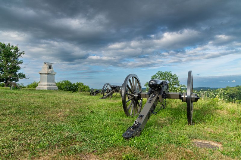 Historic cannons and memorial at Gettysburg, Pennsylvania, set against a dramatic sky.