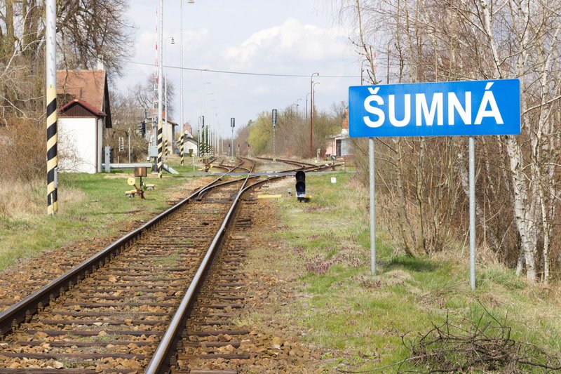Railroad tracks leading to Šumná station surrounded by spring foliage.