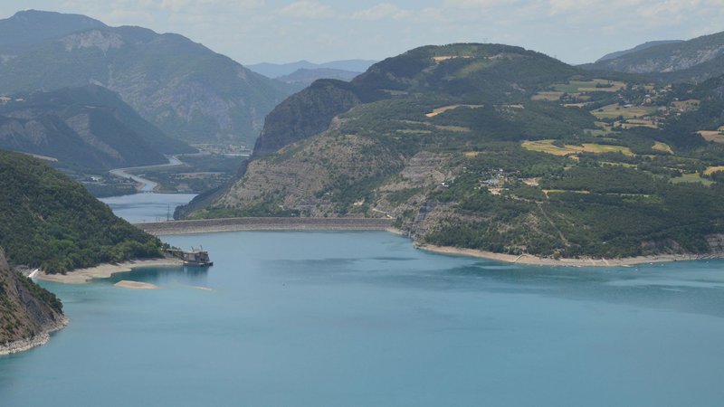 Stunning aerial view of a serene lake surrounded by mountains and a visible dam.