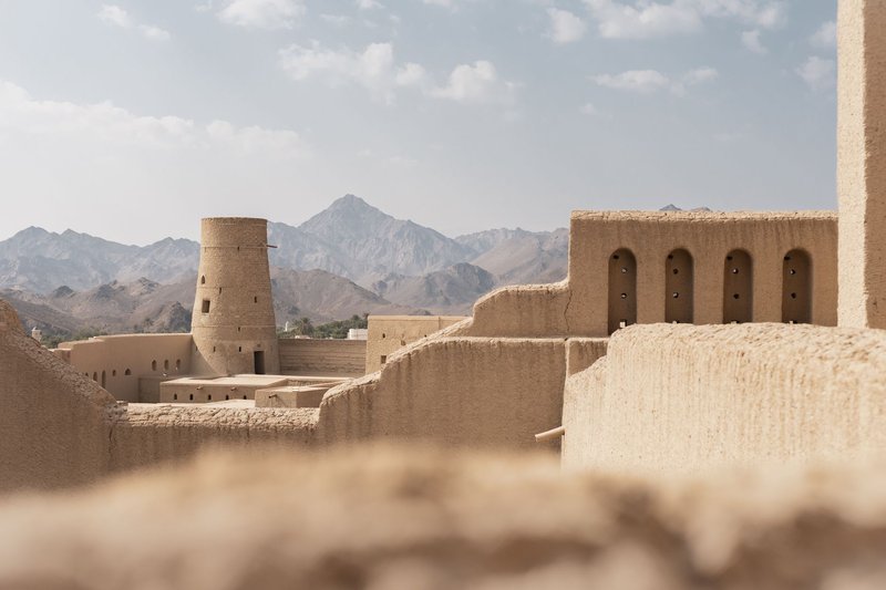 Traditional Omani fortress architecture with mountain backdrop, showcasing the cultural heritage of Nizwa.