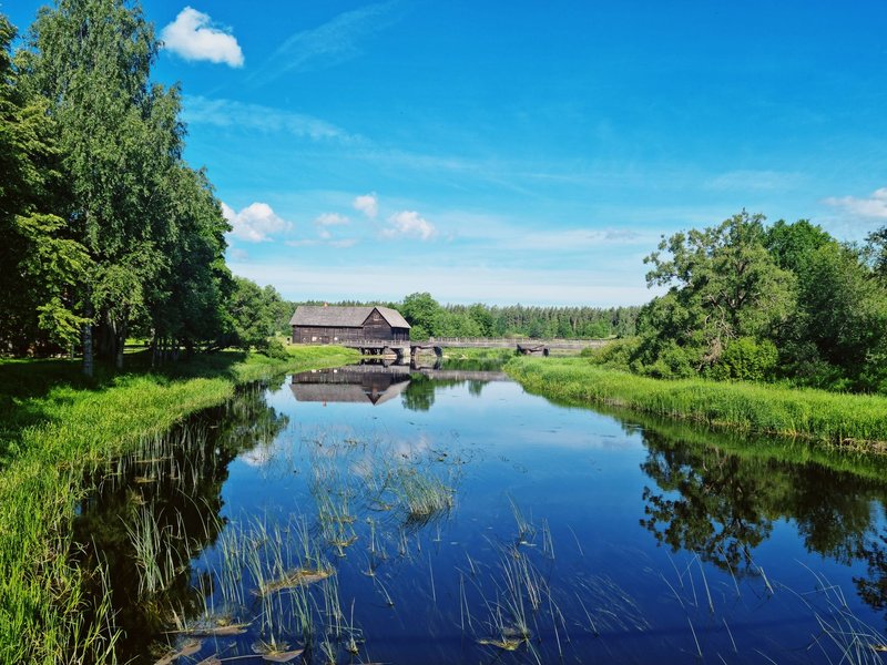 Beautiful rural landscape with a wooden house by a tranquil lake in Estonia.
