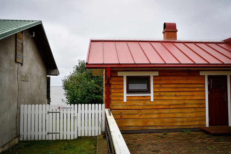 A quaint wooden house with a red roof near Lake Peipsi in Tartu County, Estonia.