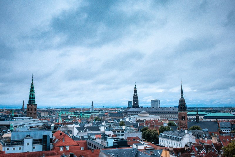 Wide-angle view of Copenhagen's historic architecture and skyline under overcast skies. Ideal for urban exploration themes.