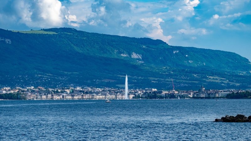 Breathtaking panorama of Geneva cityscape and iconic Jet d'Eau fountain under a clear sky.