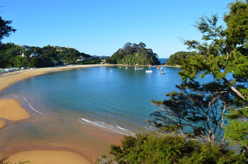 Explore the serene beauty of Kaiteriteri Beach, featuring golden sands and clear waters under a bright summer sky.