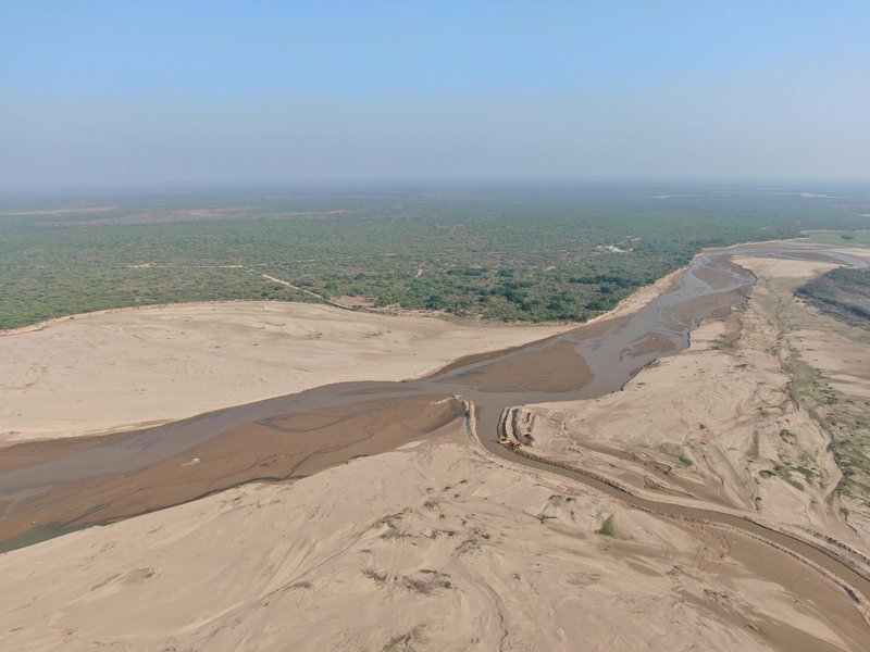 Aerial shot of an arid river landscape in La Dorada, Paraguay, showcasing sandy dunes and vegetation.