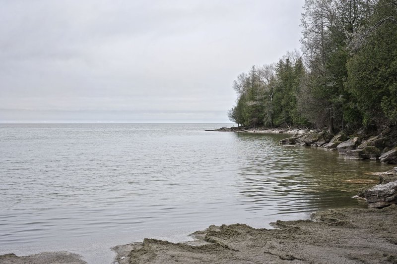 Peaceful view of Lake Michigan's shore in Wisconsin with calm waters and rocky landscape.
