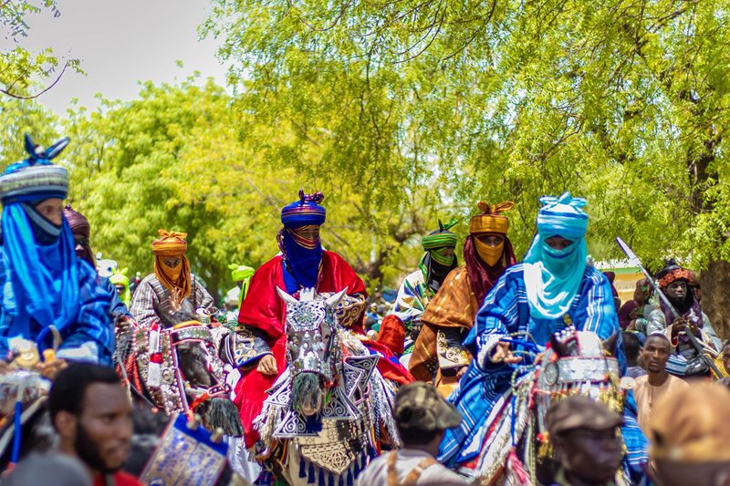 Vibrant group of African horsemen in traditional attire during a colorful cultural parade.