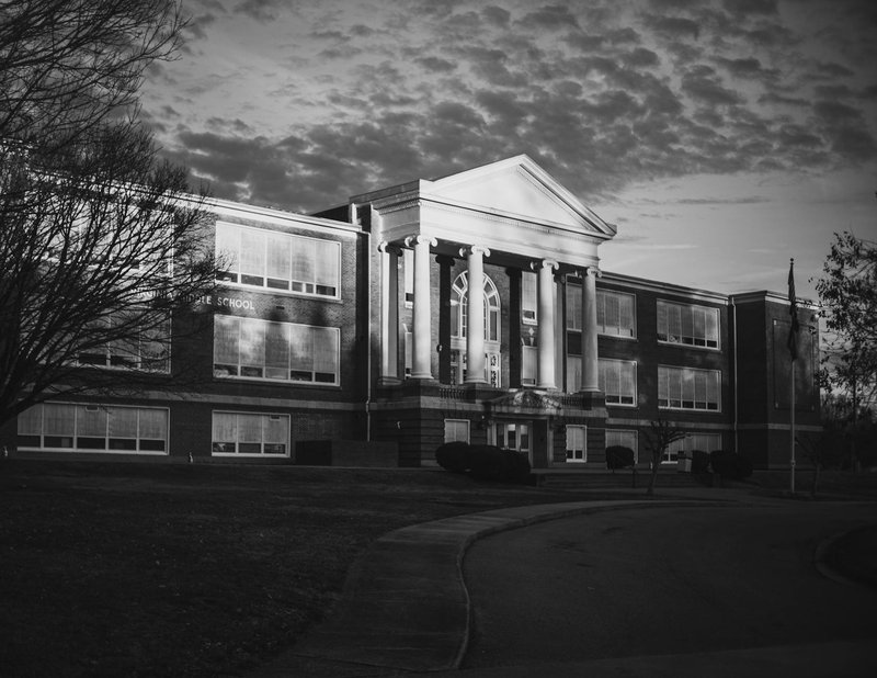 Classic black and white photo of a historic school building with dramatic lighting at dusk.