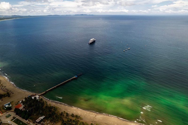 Stunning aerial shot of Tela beach in Honduras featuring a dock and ship in vibrant waters.
