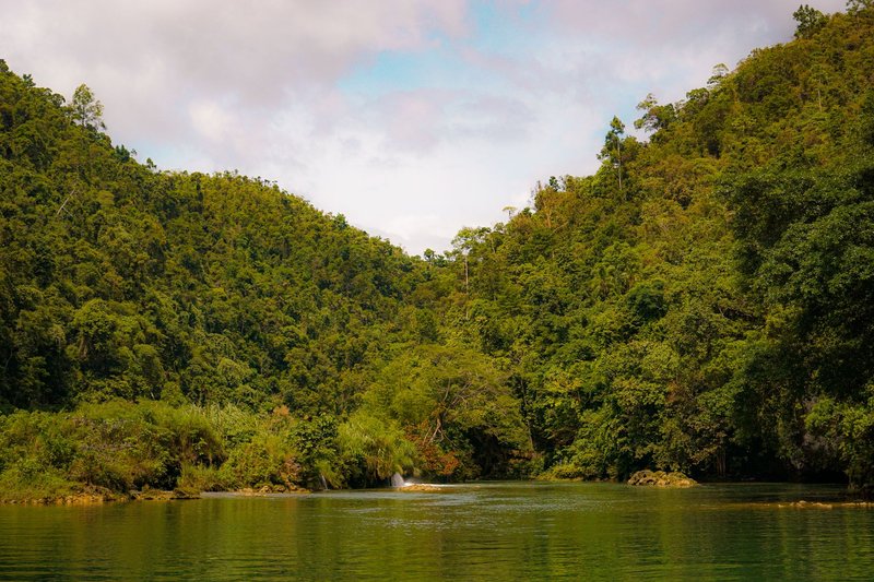Tranquil view of a river surrounded by lush green forests and hills, perfect for nature enthusiasts.